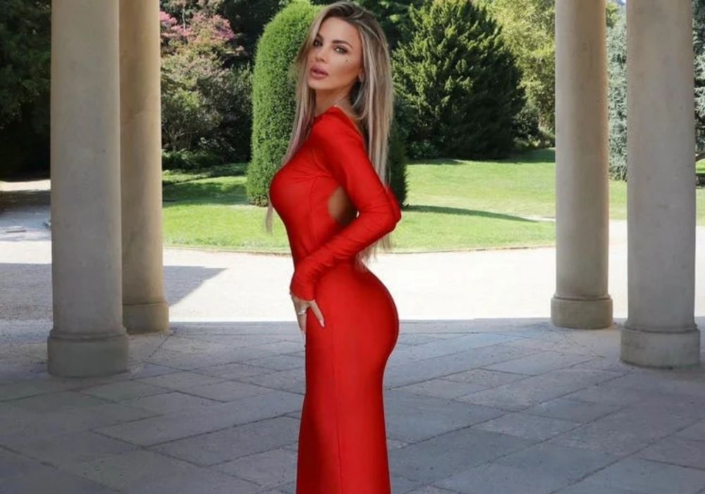 Woman in a bikini cover up dress standing in front of classical columns with greenery in the background